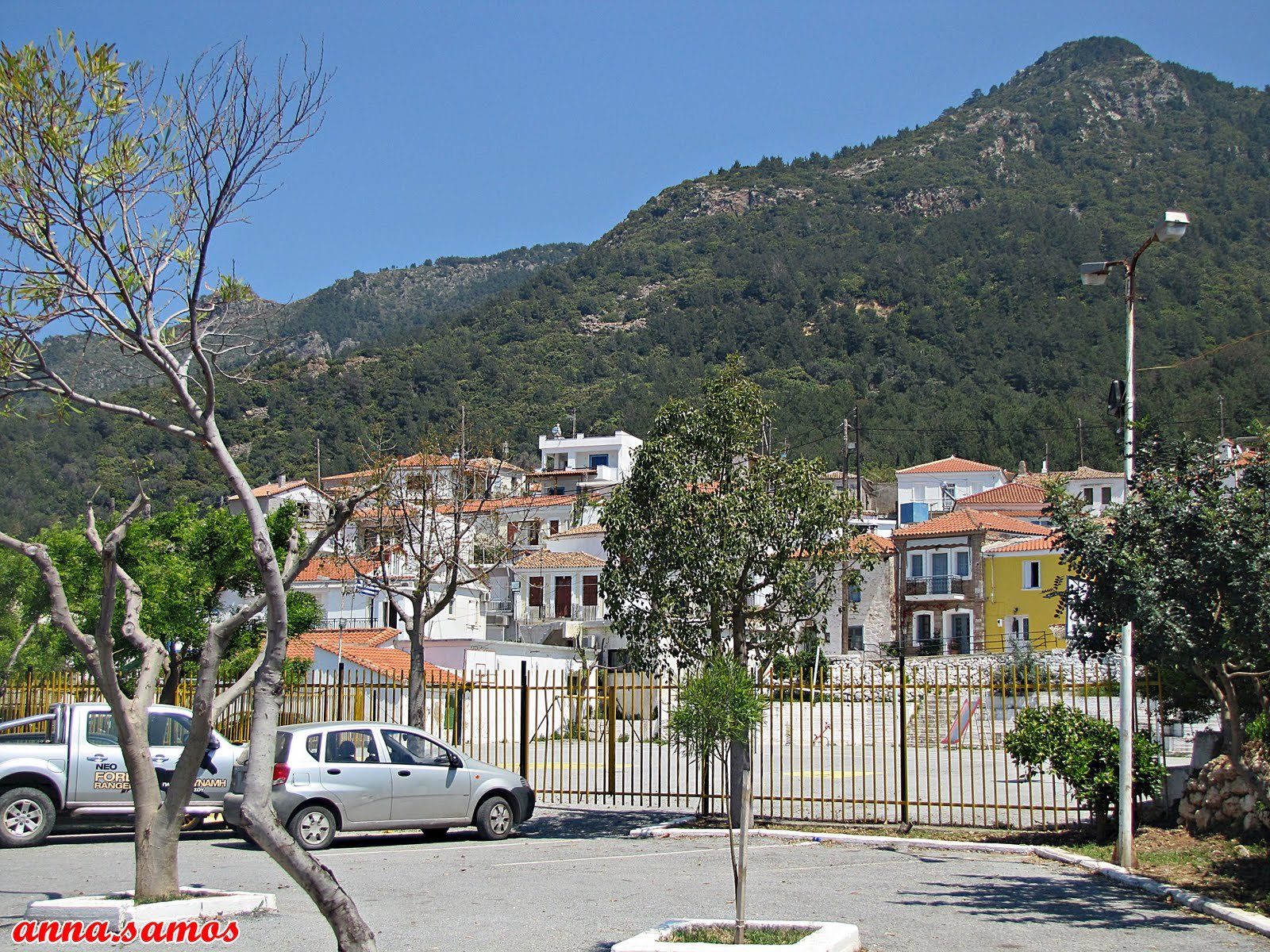 Partial view of Ydroussa, Samos, from the parking area, showing stone houses and slopes.