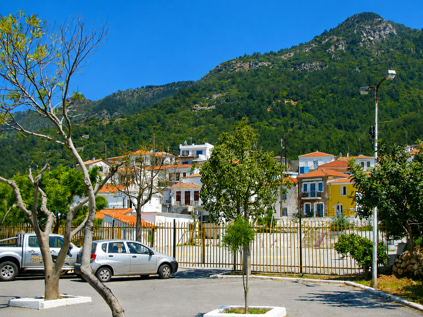 Deelzicht op Ydroussa op Samos vanaf de parkeerplaats, met huizen en helling.