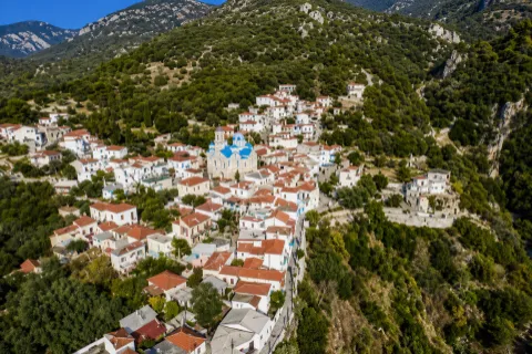 Aerial view of Skouraika, Samos, showing stone-built homes surrounded by greenery.