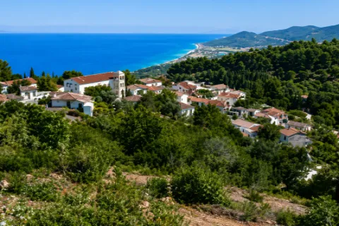 Άποψη των Σταυρινήδων Σάμου από ψηλά, με πέτρινα σπίτια και φόντο τη θάλασσα.