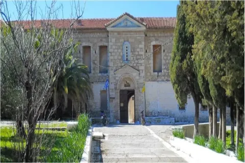 The Prophet Elias Monastery in Samos with a stone bell tower and mountain backdrop.