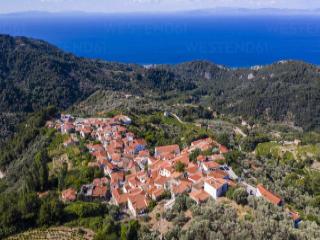 Vicoli in pietra e case tradizionali a Manolates, Samo, immersi nel verde.