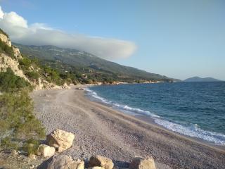 Spiaggia Perri a Samo con mare cristallino e vista sul villaggio vicino.