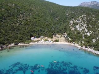 Spiaggia di Megali Lakka a Samo con costa naturale, fitta vegetazione e acque turchesi limpide